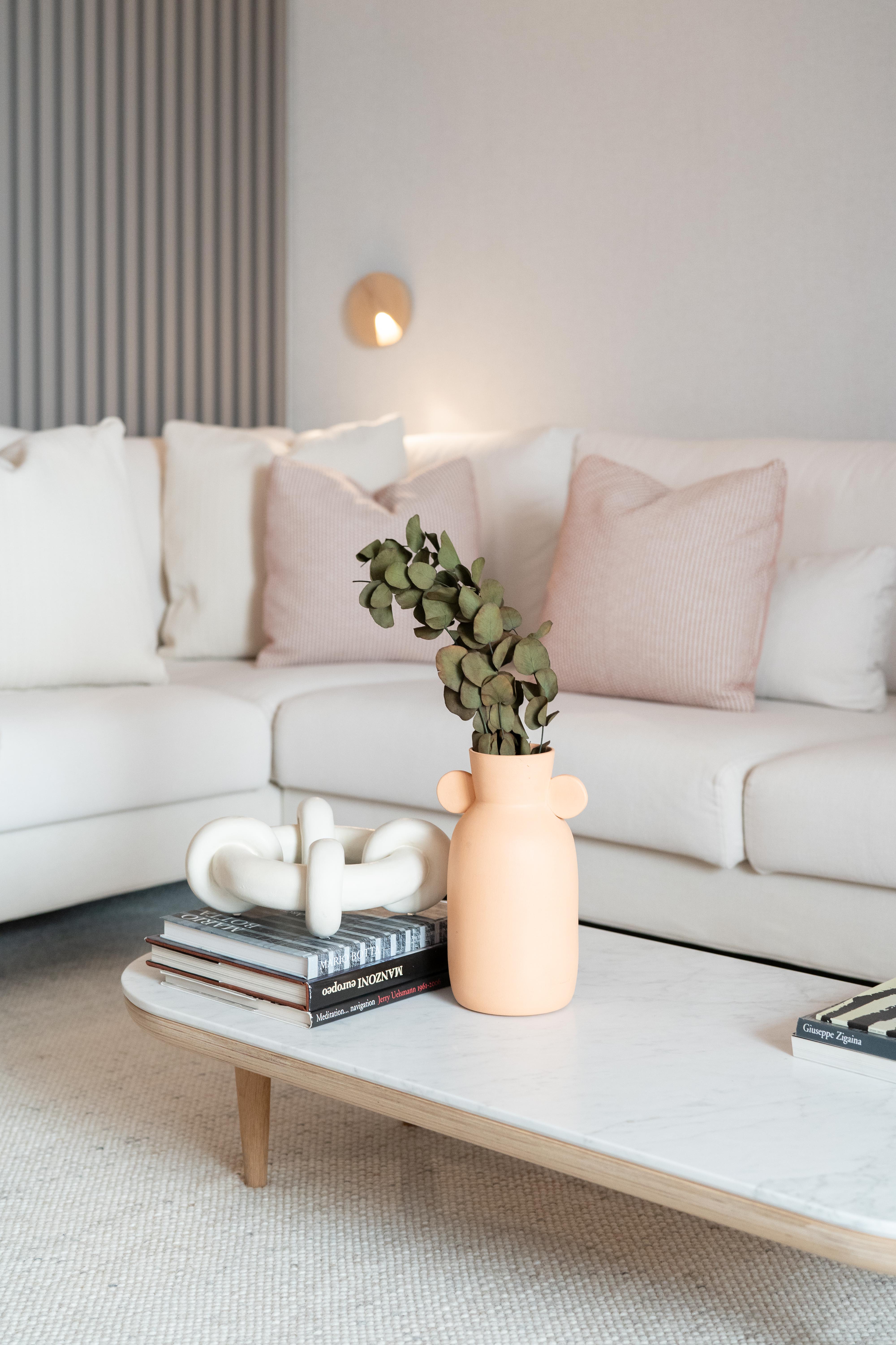 Sala de estar con sofá blanco y mesa blanca con elementos decorativos