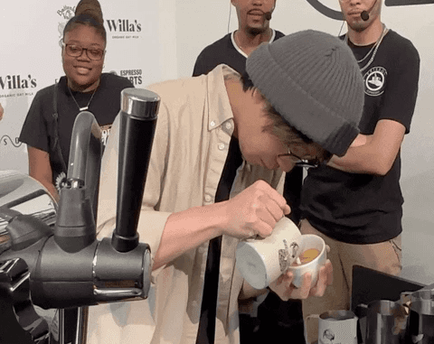 A close-up of a person wearing green-tinted glasses, with a serious expression and smooth skin.