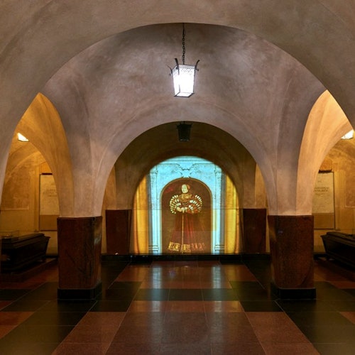 An arched corridor with a lantern hanging from the ceiling. A illuminated image of a historical figure is projected on the far wall.