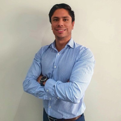 Dan Sandoval, Founder and CEO, professional headshot in red suit against gray background