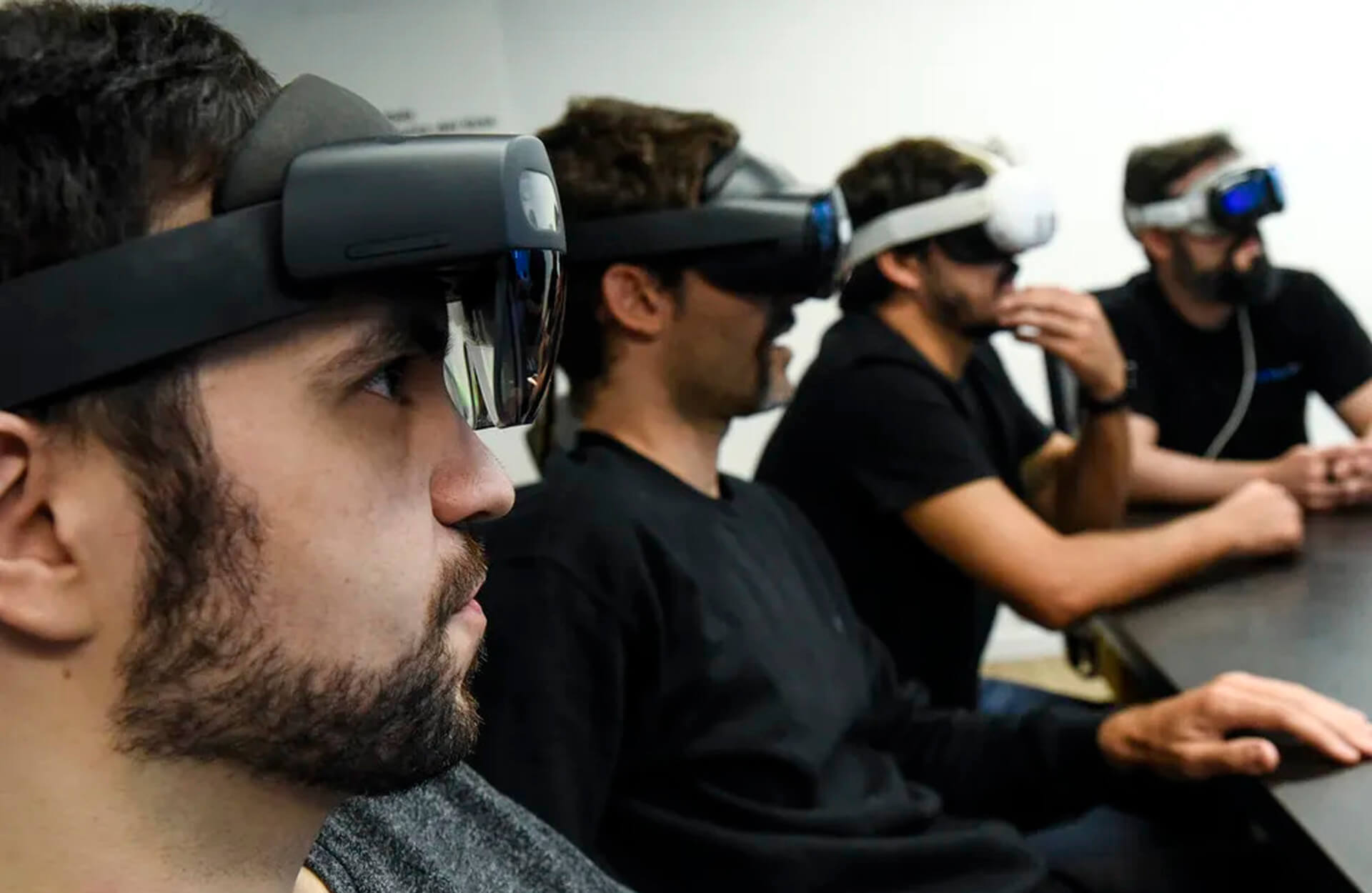 Four diverse professionals collaboratively working on a laptop, with one person pointing at the screen while others observe.