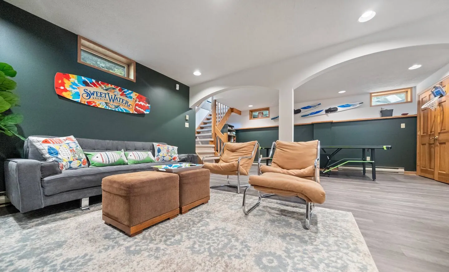 Lower level living room with gray sofa, ottomans and ski decor at Lake Front, Lake Naomi