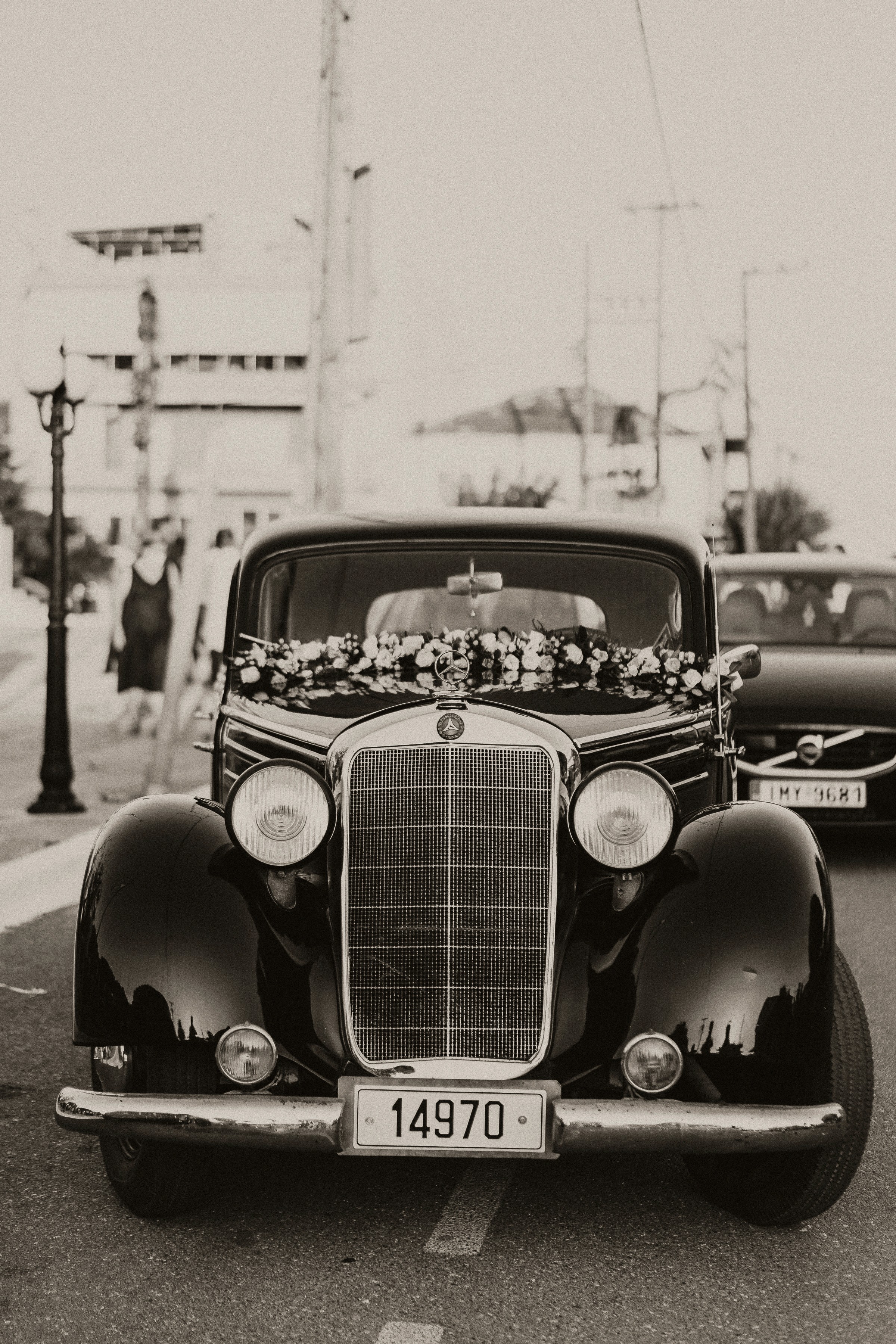 Classic vintage black wedding car decorated with a bespoke floral garland for a luxury destination wedding in Greece