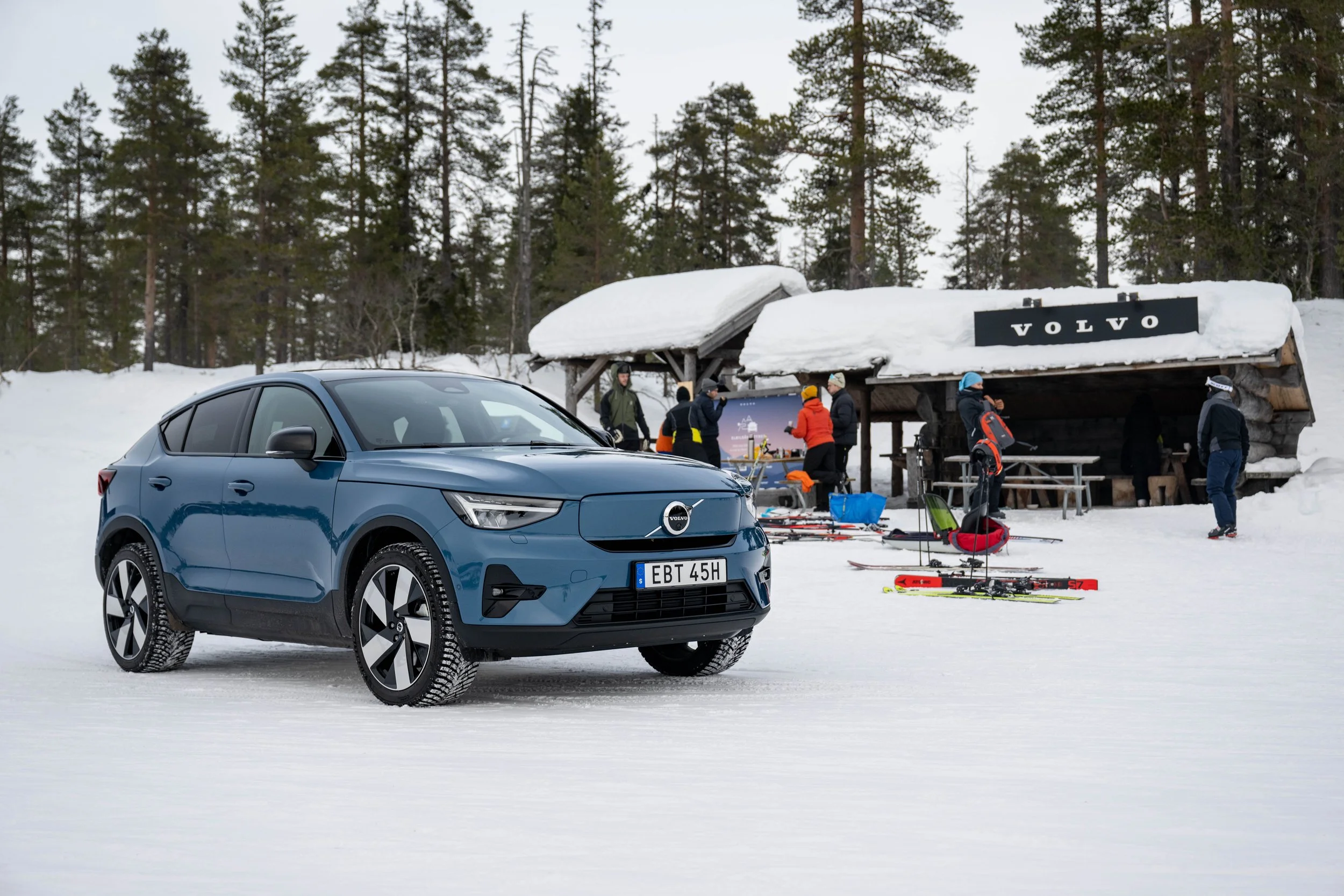 Volvo car parked in the snow in front of a ski cabin