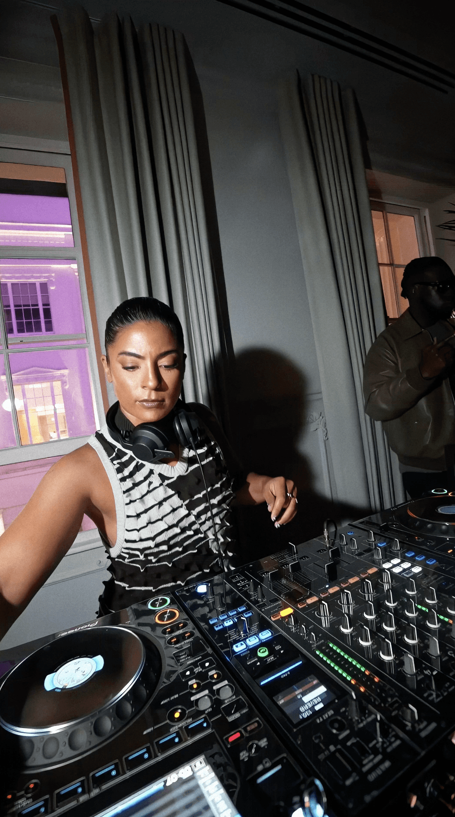 Bride sitting on ground against wall, groom standing nearby