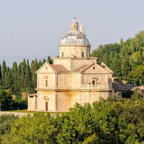 一座老式的圓頂石建築，以古典的建築風格為特點，周圍被樹木環繞，在晴天裡顯得格外美麗。