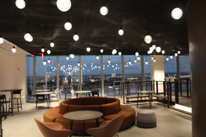 A wide shot of the room with the orange couch and hanging lights