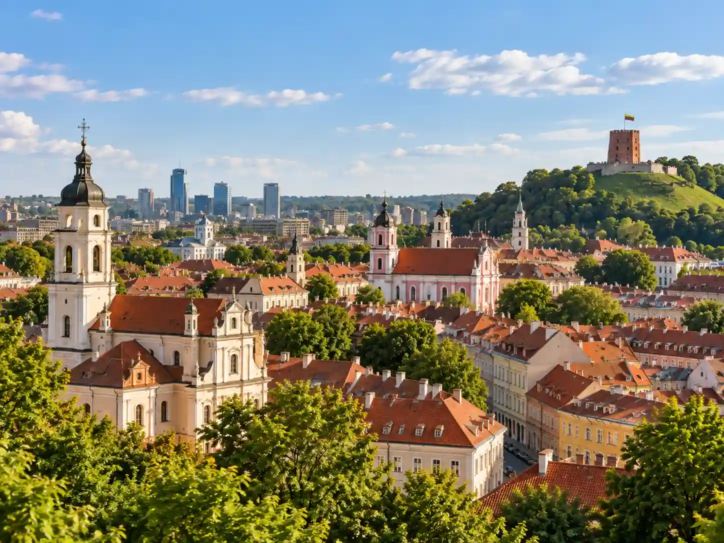 View of Vilnius Old Town in Lithuania with historic church towers, red rooftops and Gediminas Castle Tower on the hill.