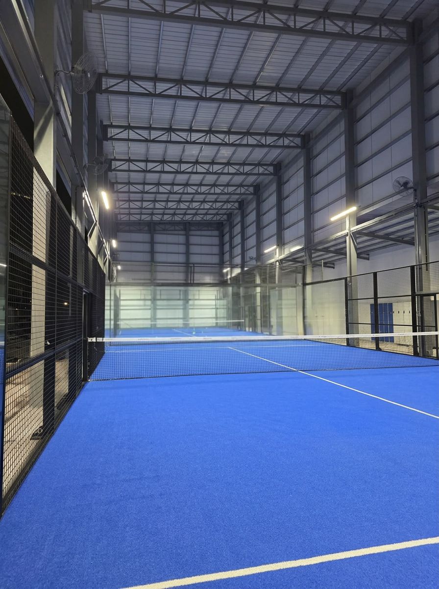 a tennis court with a blue tennis court and buildings in the background
