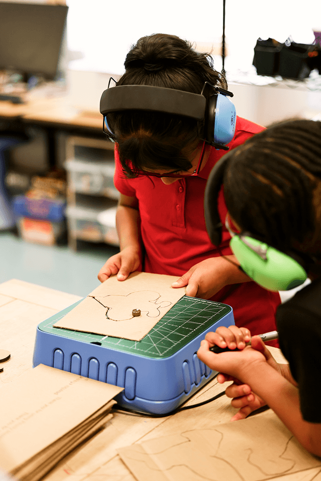 Two elementary students working on a project that involves innovation, technique, and modern technology.