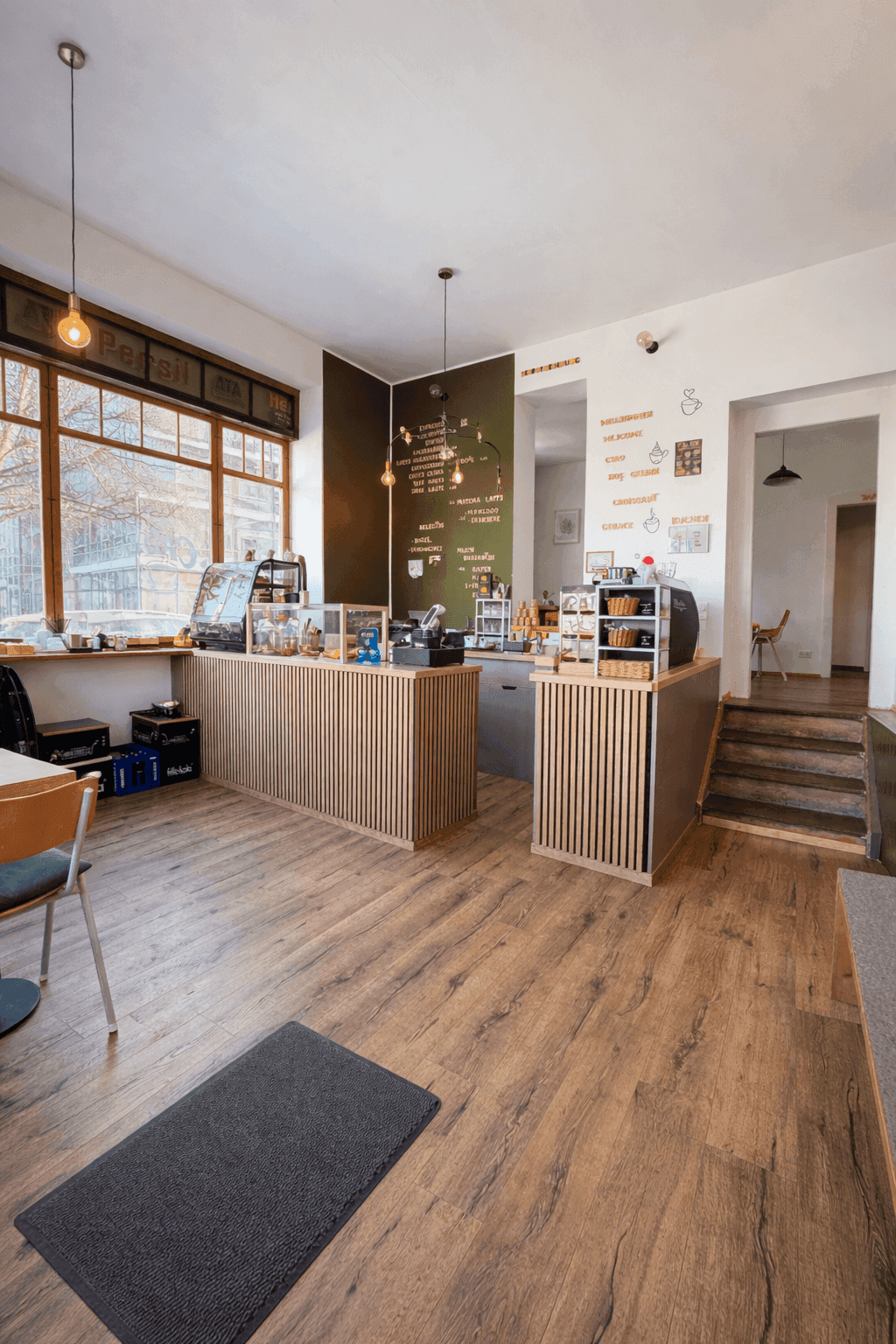 A modern reception area featuring wooden flooring, a stylish front desk, and large windows with natural light.