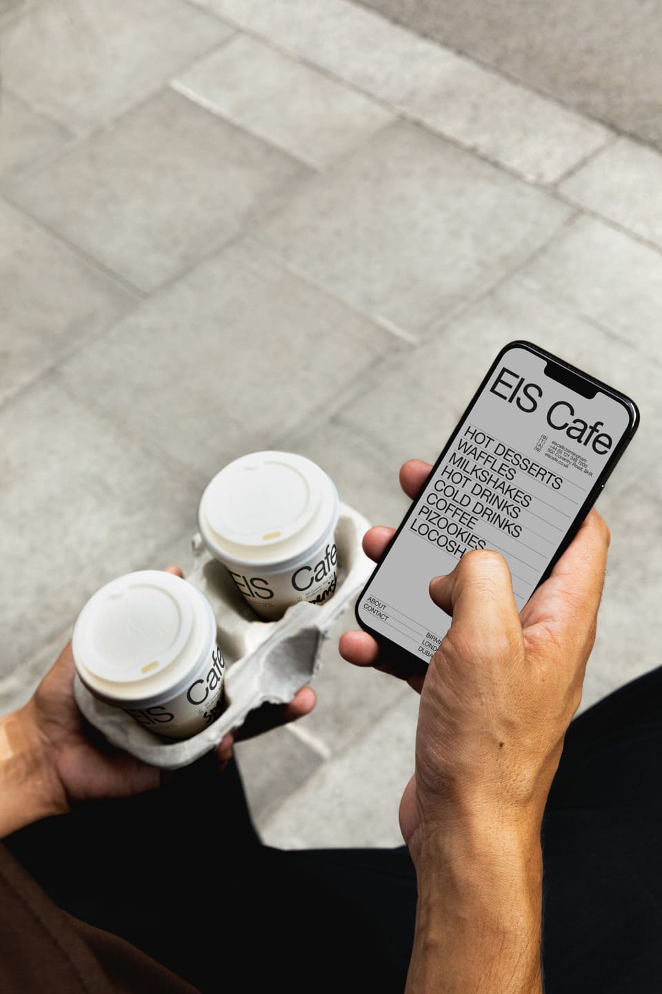 A photo of a phone and coffe from EIS Cafe holded by a person.