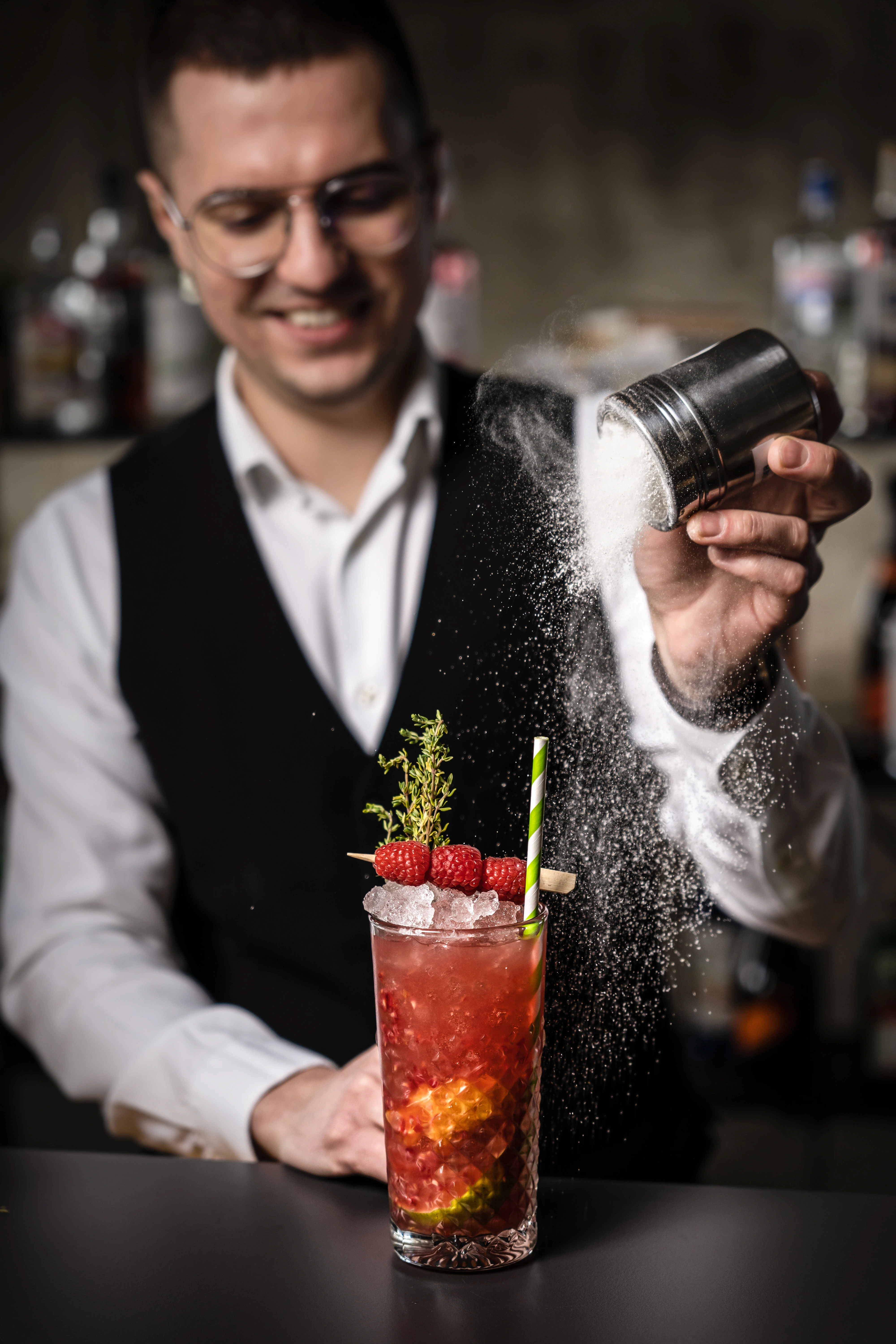 Barman na weselu pokazuje sztuczki barmańskie przed zgromadzonymi gośćmi podczas pokazu barmańskiego