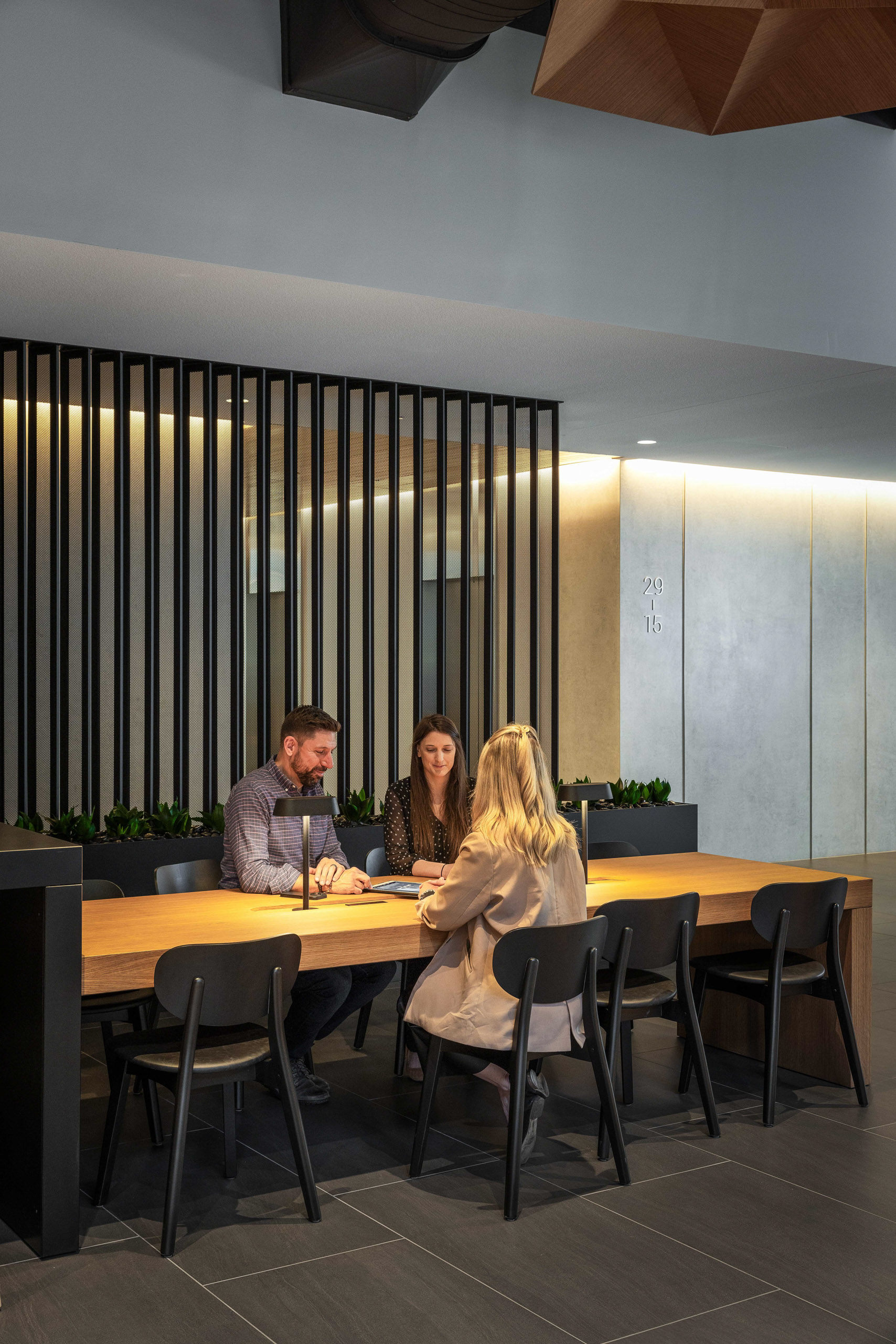 Three people at a wooden table with laptops