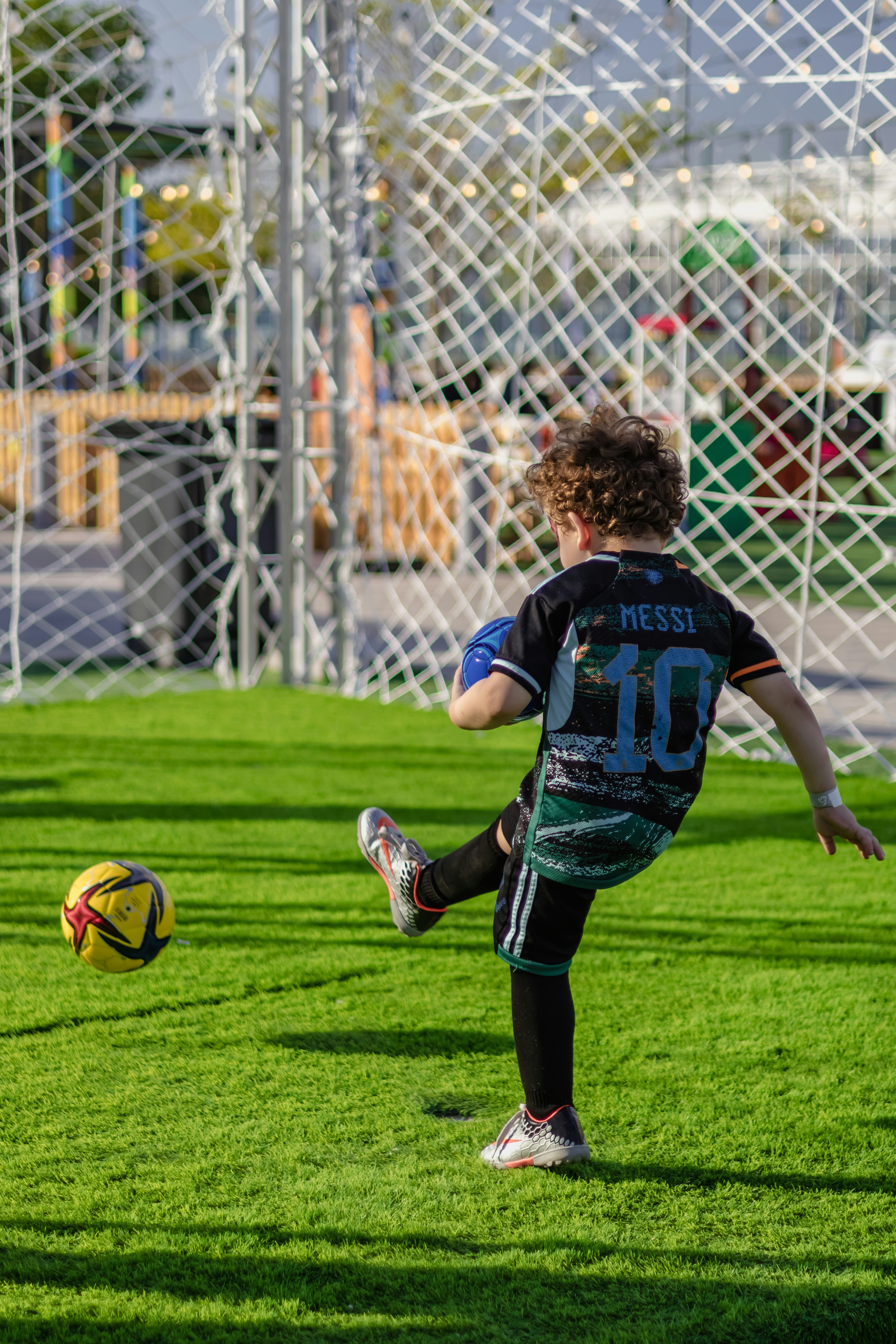 A boy kicks a soccer ball on a green field.