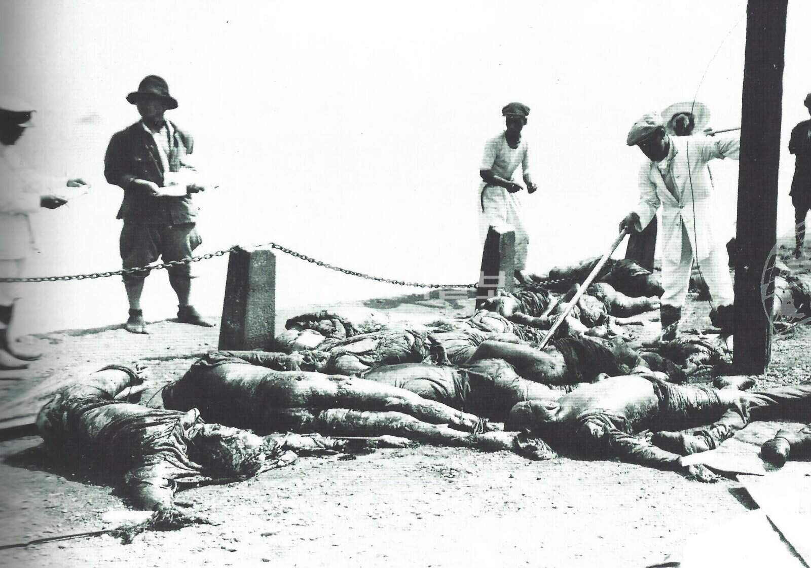 Hình ảnh lịch sử liên quan đến vụ thảm sát Quan Đông 1923. Một cảnh sát cấp cao Nhật Bản đang dùng gậy chọc vào bộ phận sinh dục của một thi thể nữ, nơi xảy ra là một con đê ven biển.