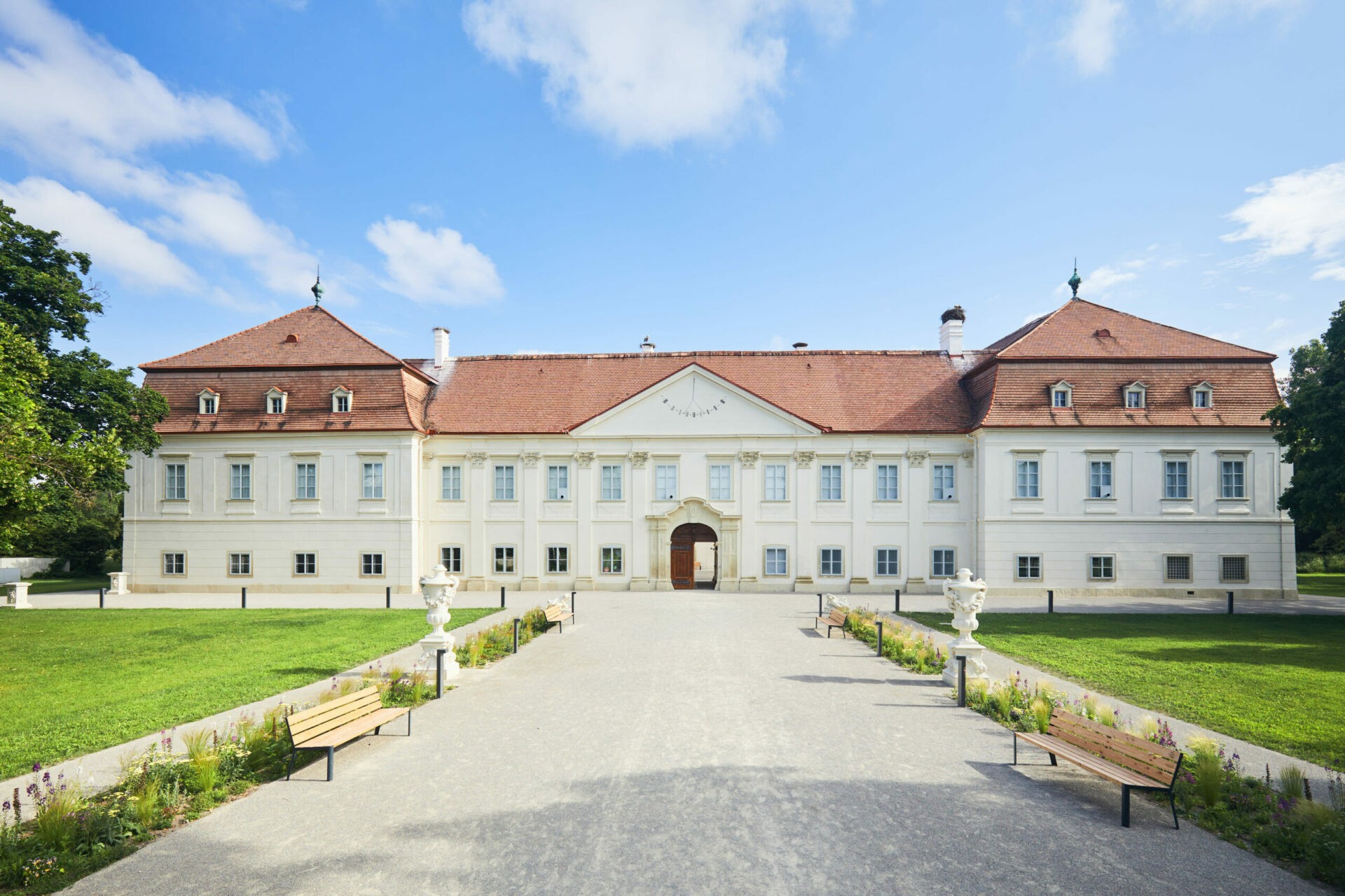 Schloss Hof in Frontansicht mit rotem Dach und Gartenweg