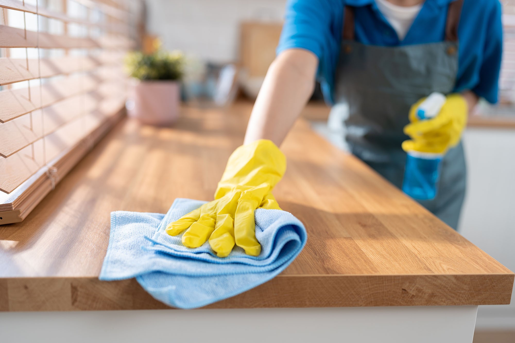 A close-up hand of an Adams Care expert cleaner wiping the part of a kitchen table for a post-construction house cleaning