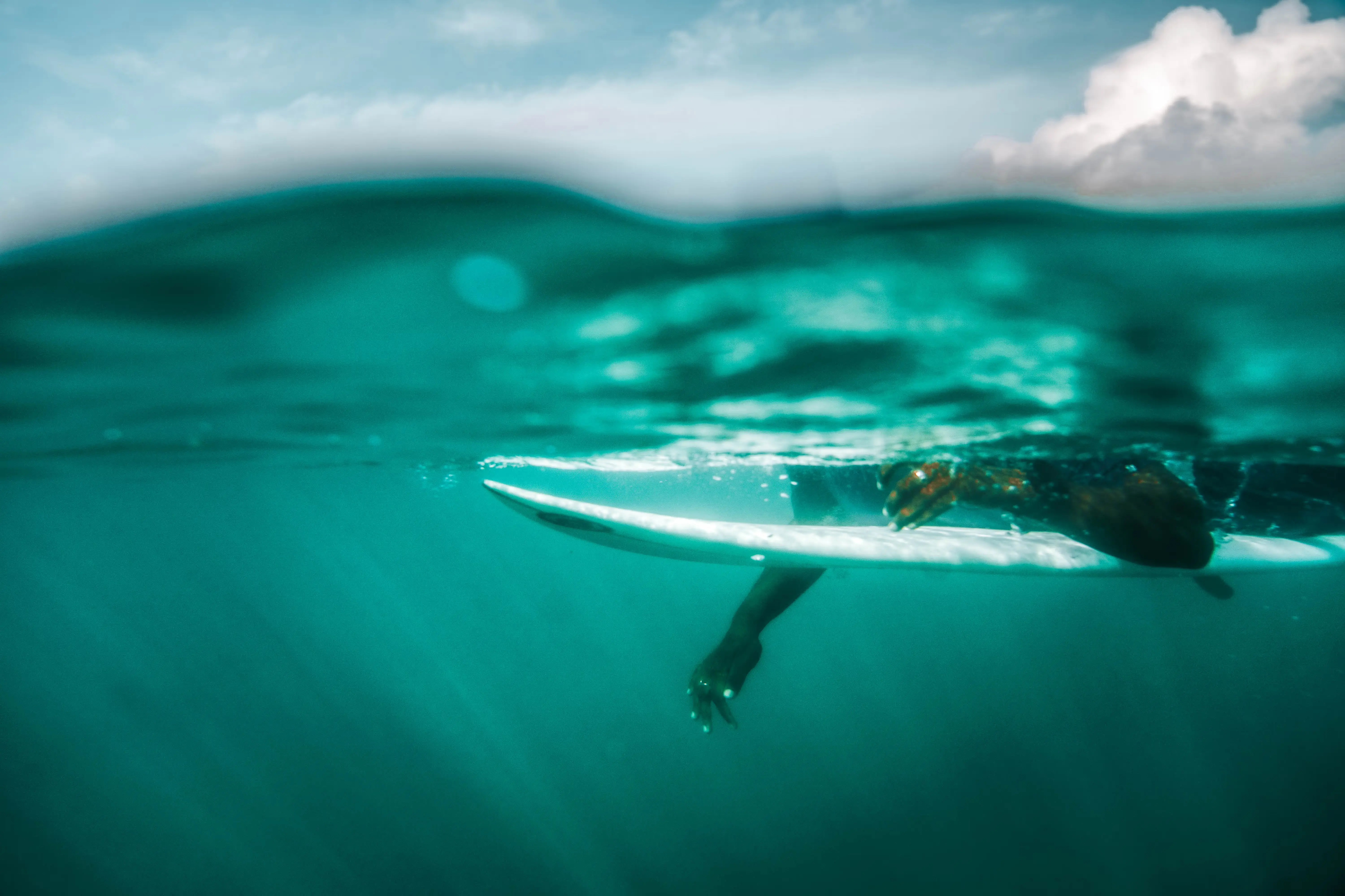 Swimmer with surfboard underwater.
