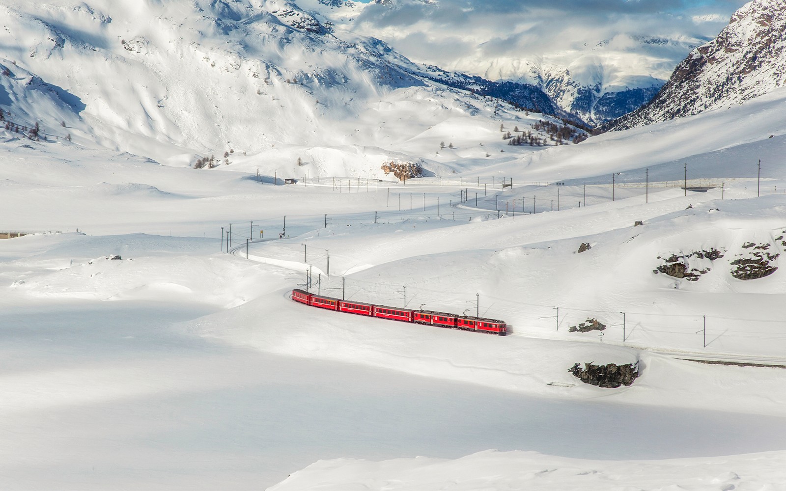 Karlarla kaplı İsviçre Alpleri manzarasında seyahat eden Bernina treni.