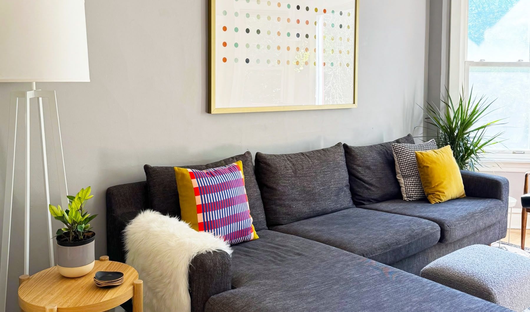 gray sectional with pillow and large polka dot art