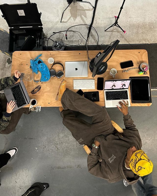 Pro web designer working at a table with laptops and equipment.