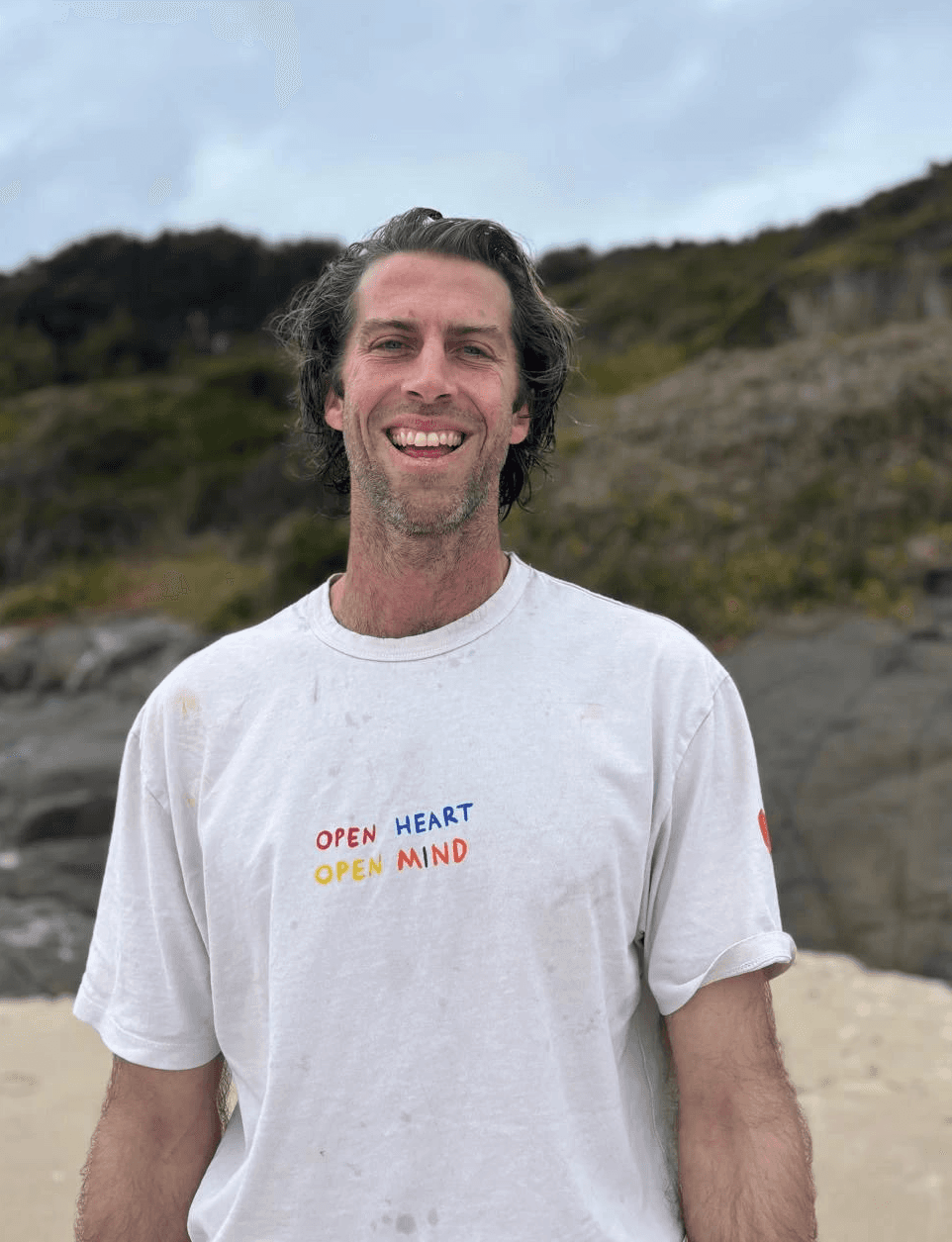 Nic Laidlaw smiling on a beach with a grey sky
