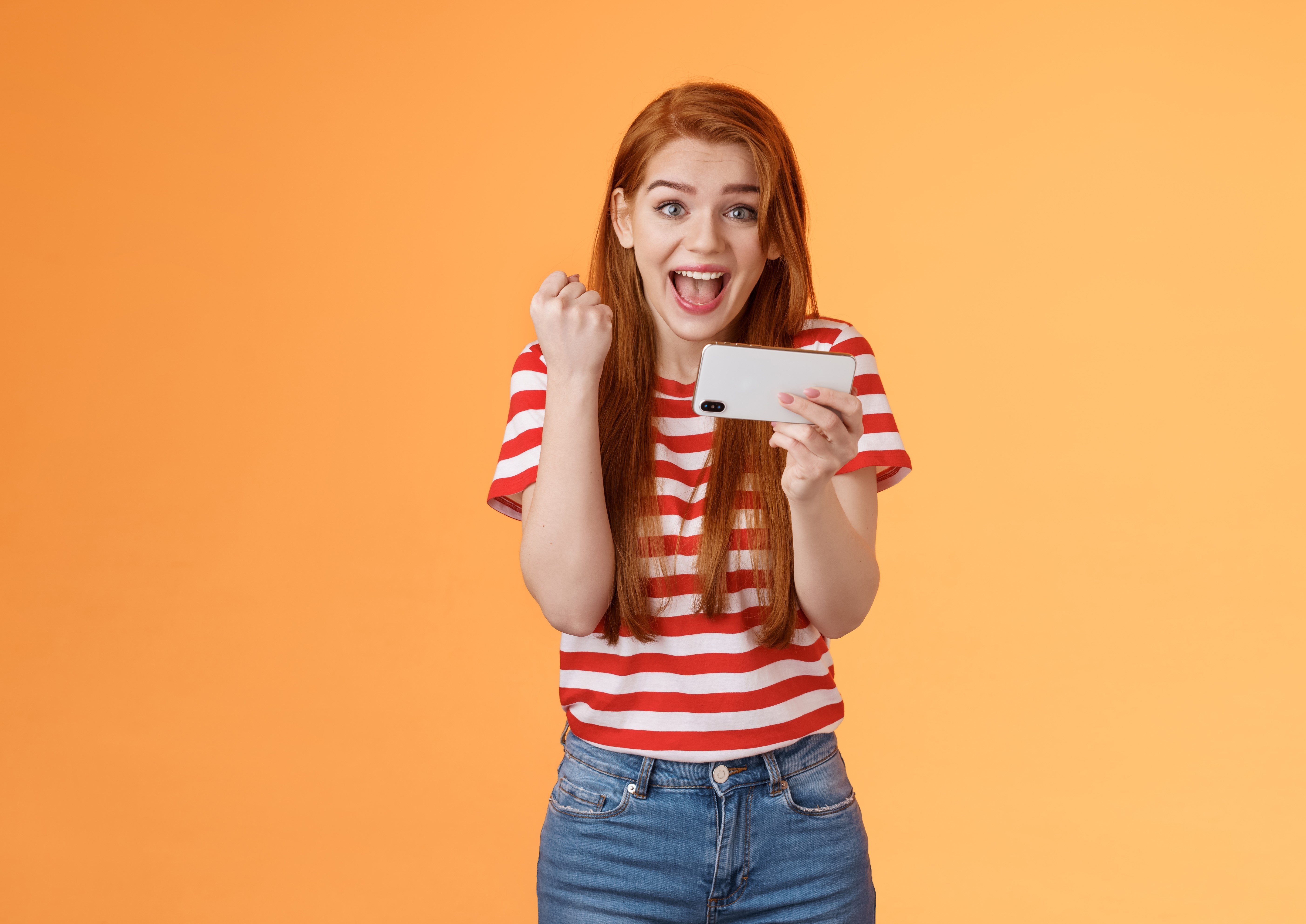 Excited creator holding smartphone celebrating discount win, representing TikTok Shop LIVE coupon conversions and viewer engagement.