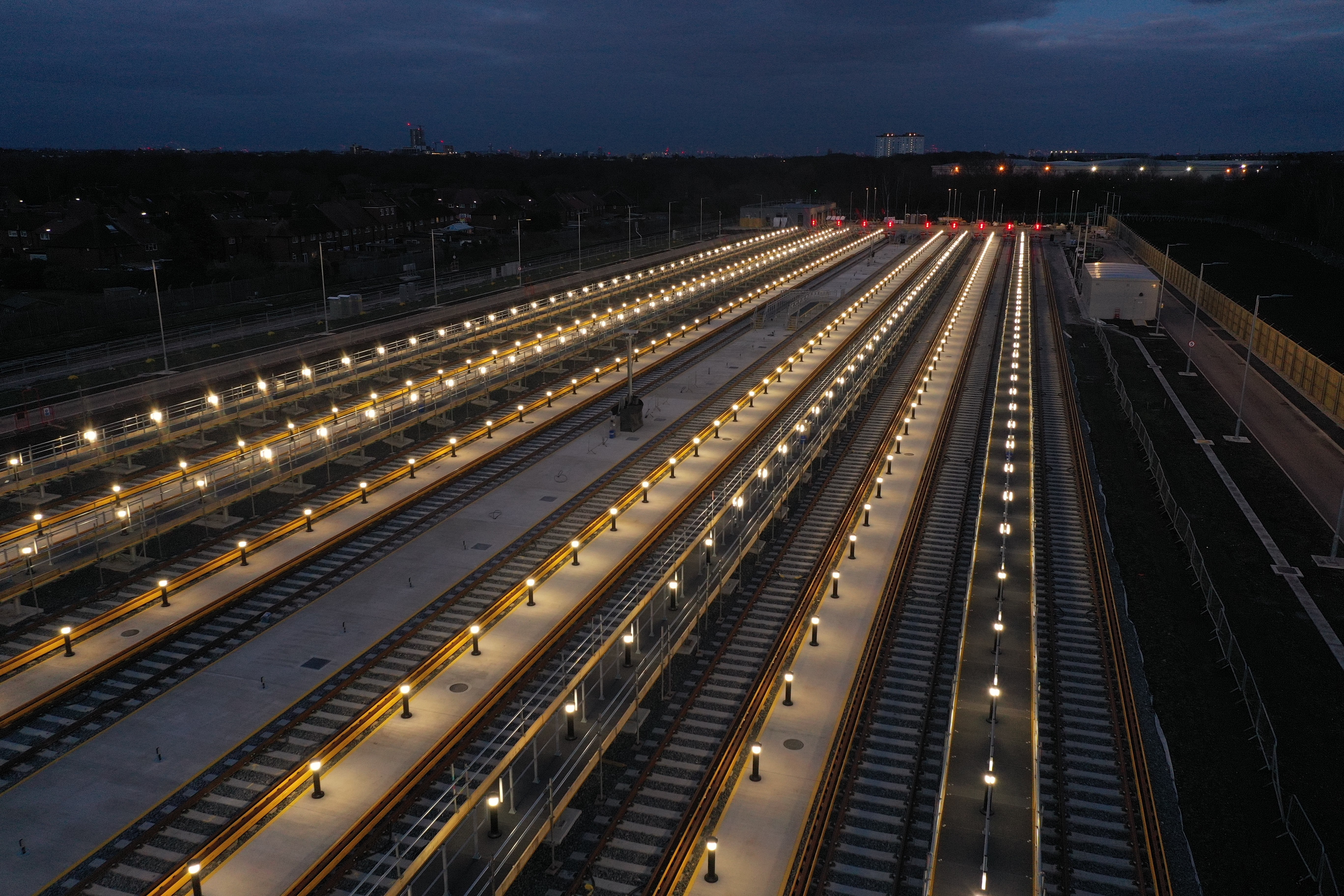 Modern building with a sleek glass facade and illuminated orange lighting, reflecting on a polished surface, creating a futuristic and elegant atmosphere