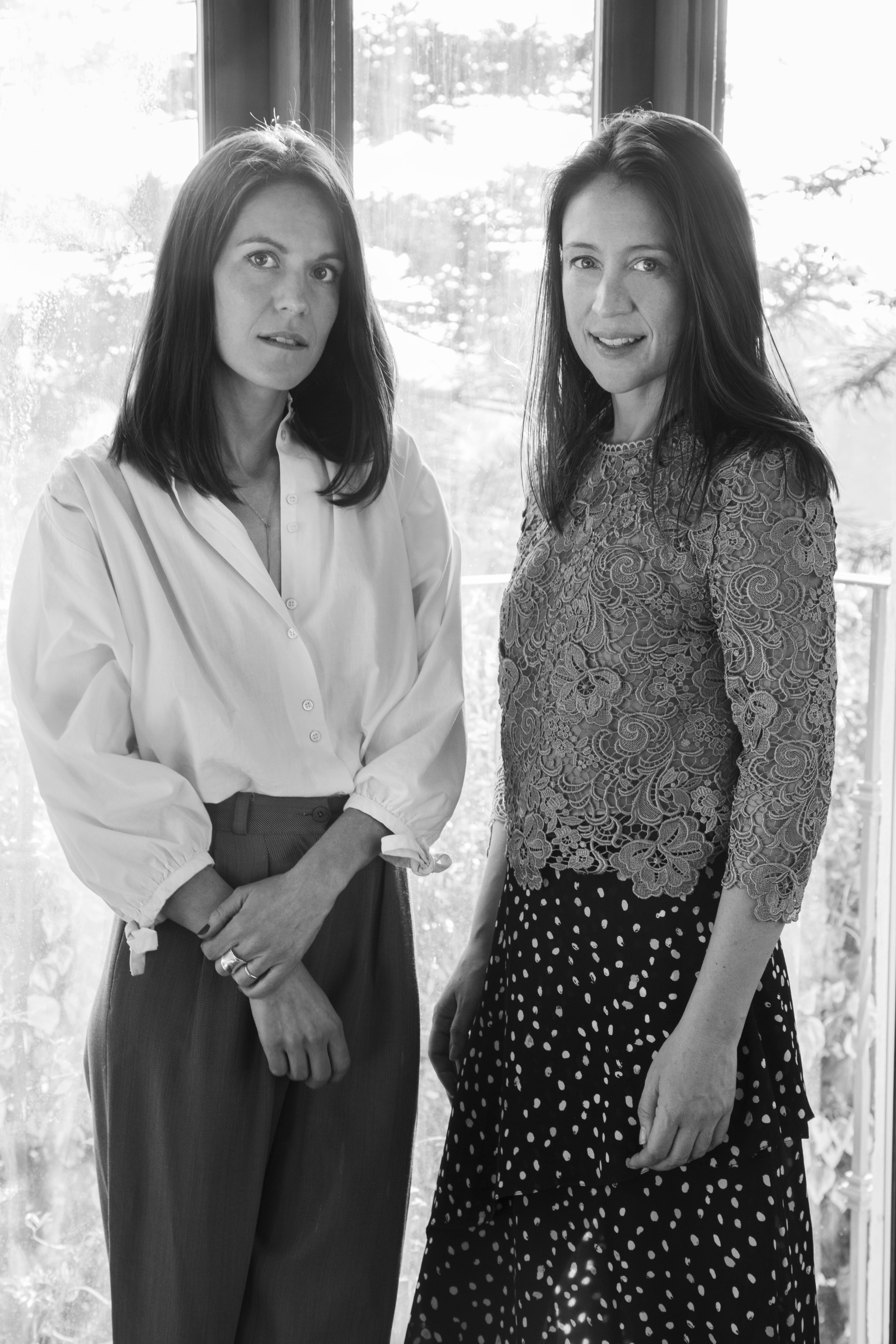 Two white women with long brown hair standing face to face.