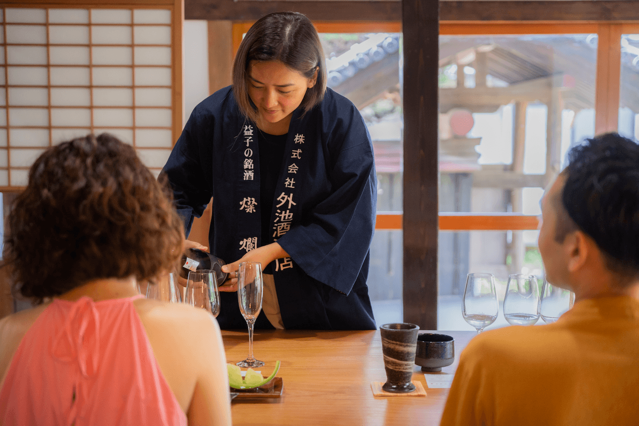 Sake somelier pouring sake into a glass in front of guests