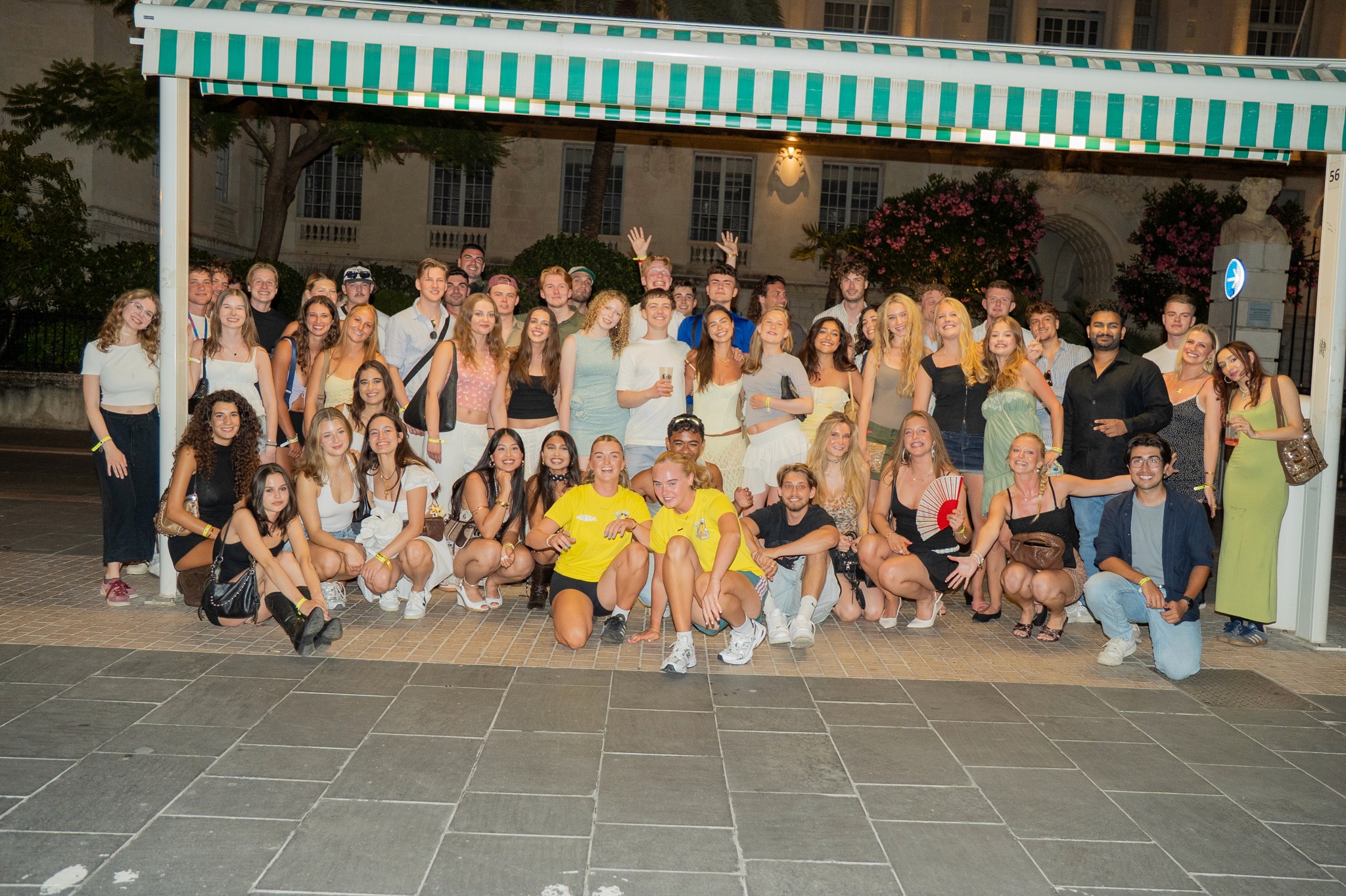 Large group of international travelers posing together at the start of a pub crawl in Nice showing a social group nightlife experience in the French Riviera