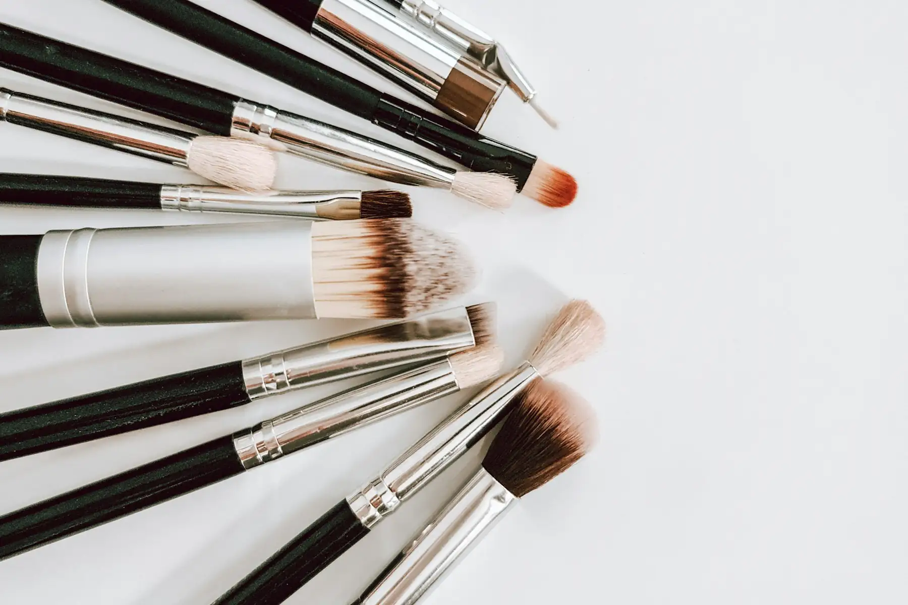A collection of black and brown makeup brushes laid out in a fan