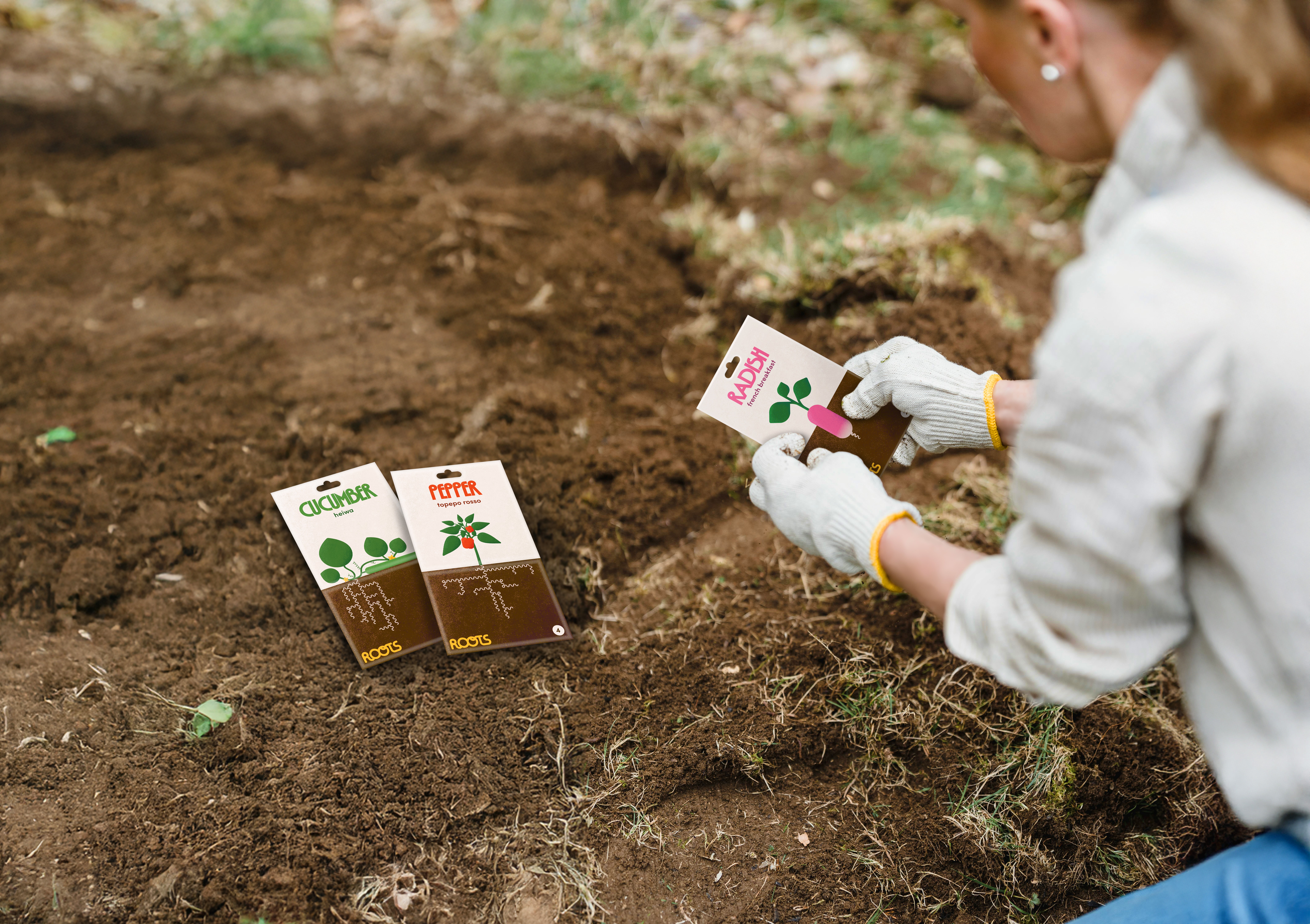 Perconne tenant un sachet de graines de radis, sachet de graines de concombre et de poivron par terre