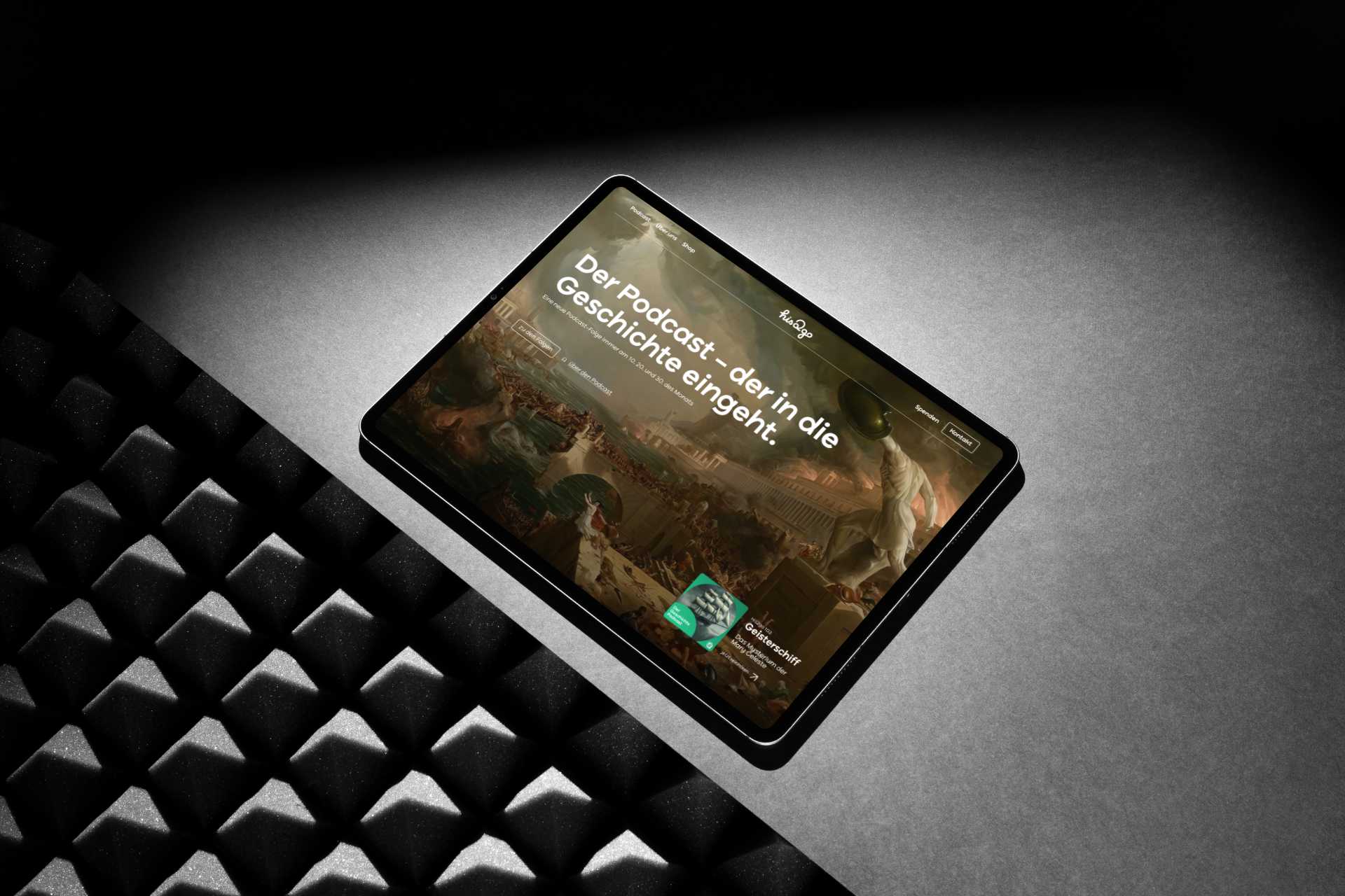 Tablet mit der His2go Website Startseite. Zu sehen ist ein historisches Bild im Hintergrund, eine große Headline und ein Podcastcover.