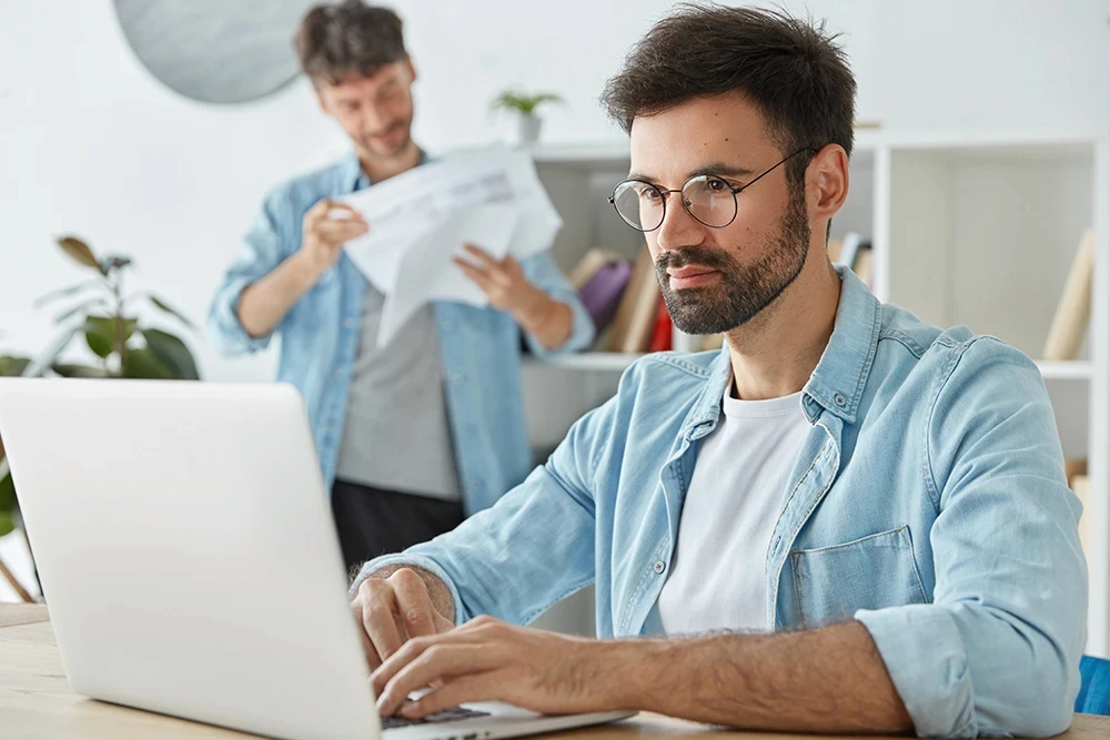 IT specialist focused and working intensely at a computer in an office.