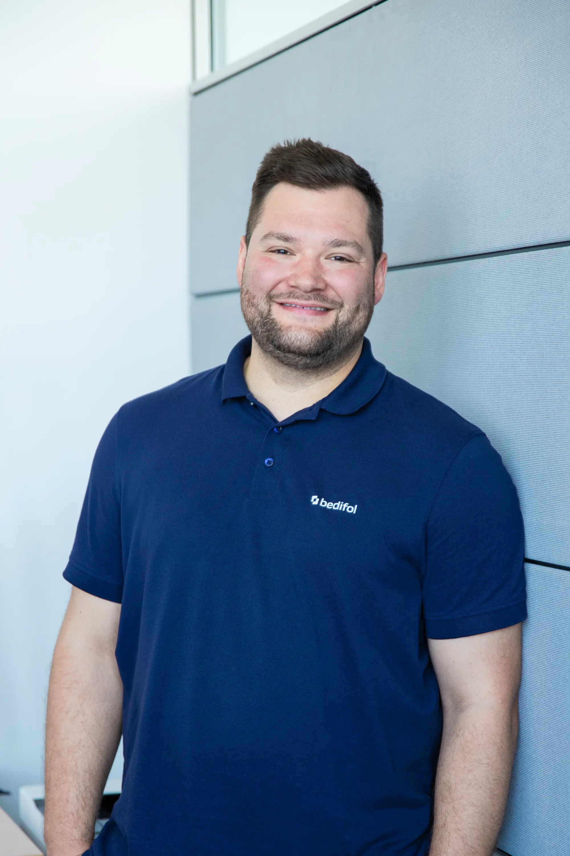 A man in a dark blue Bedifol polo shirt.