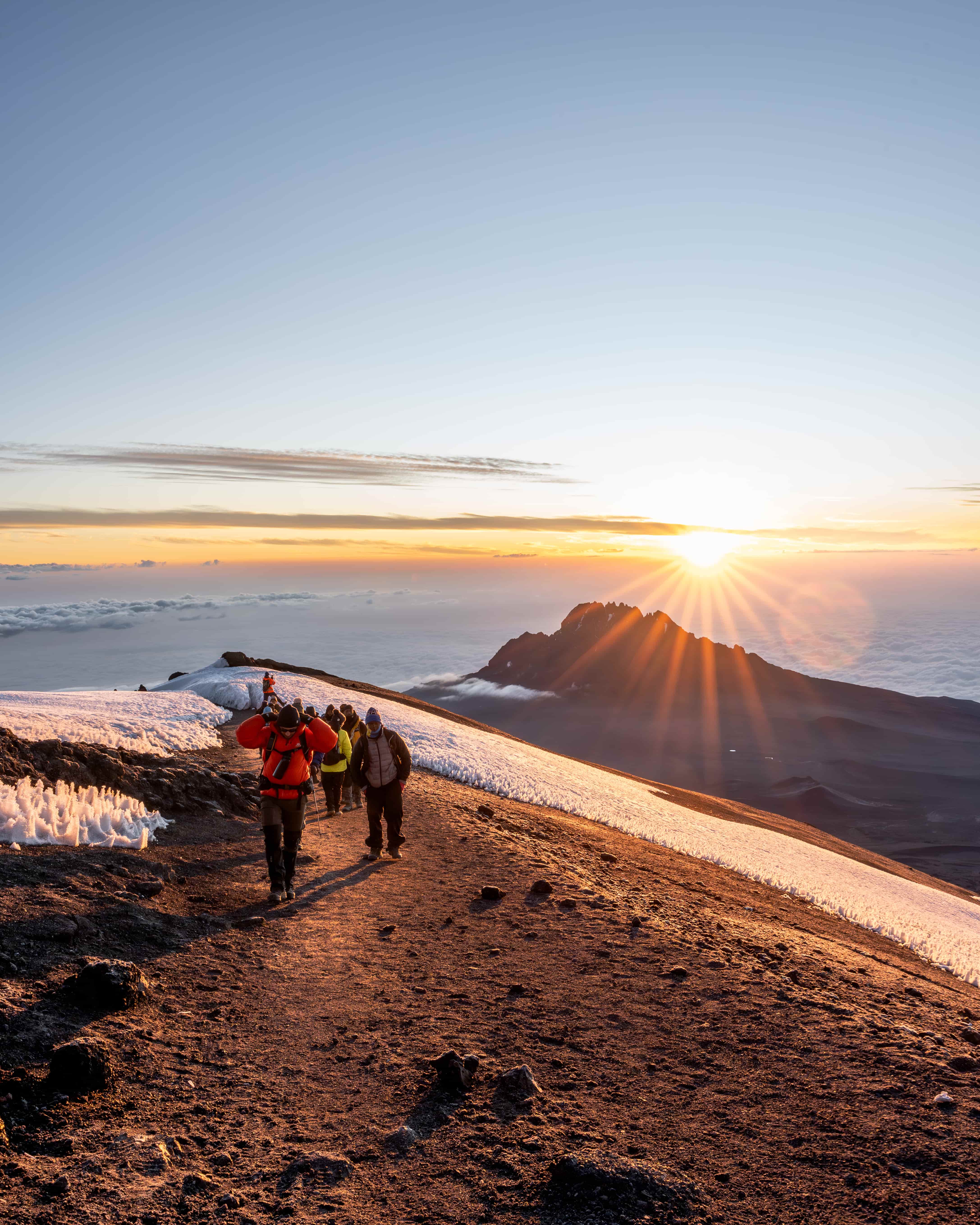 Climbers approaching the summit of Kilimanjaro in clear dry-season conditions during peak climbing season in July and August.