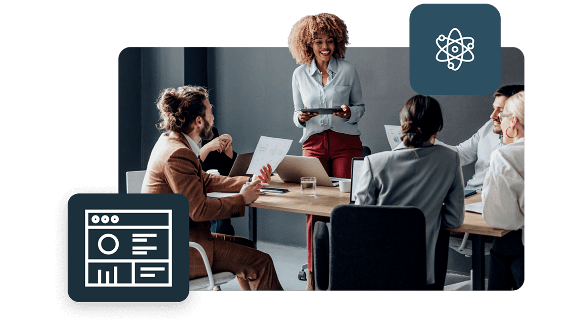 A professional team in a business meeting around a wooden table in a bright office. Two stylized dark blue icons are overlaid: one representing a data dashboard/analytics and another featuring an atom symbol. A woman stands leading the presentation while others look on.