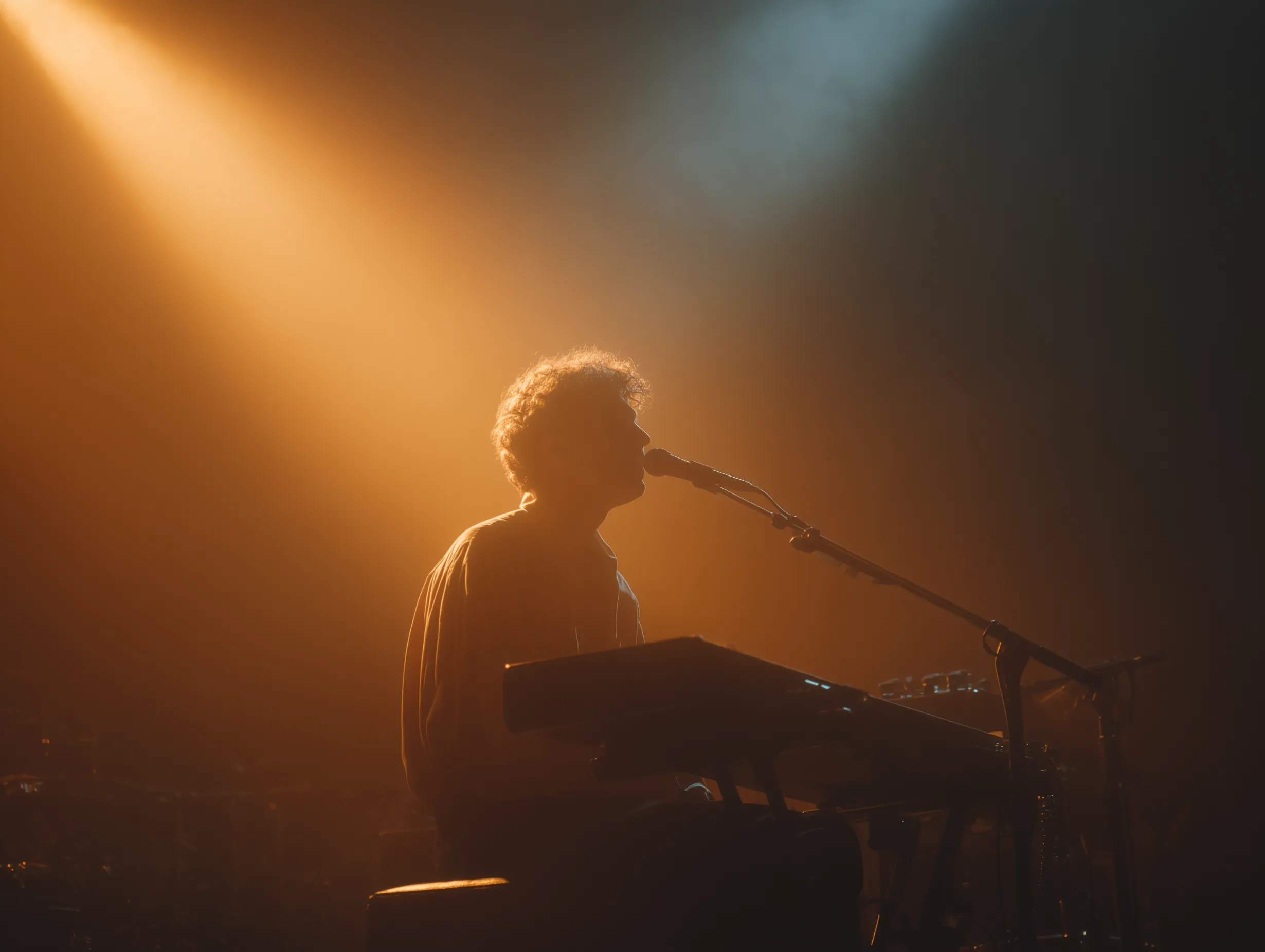 Keyboardist singing, silhouetted by bright orange light