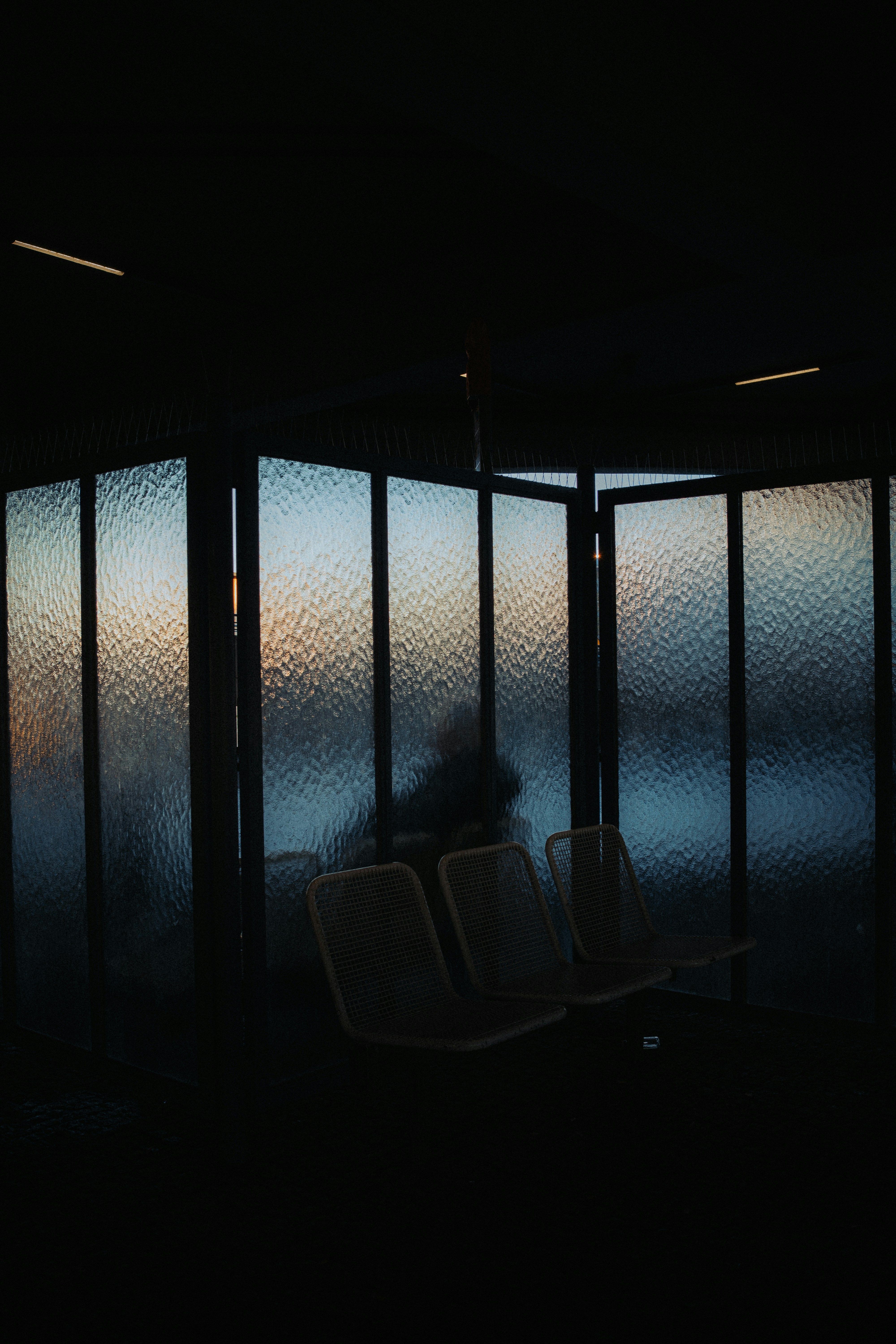 Silhouetted figure behind frosted glass panels at dusk