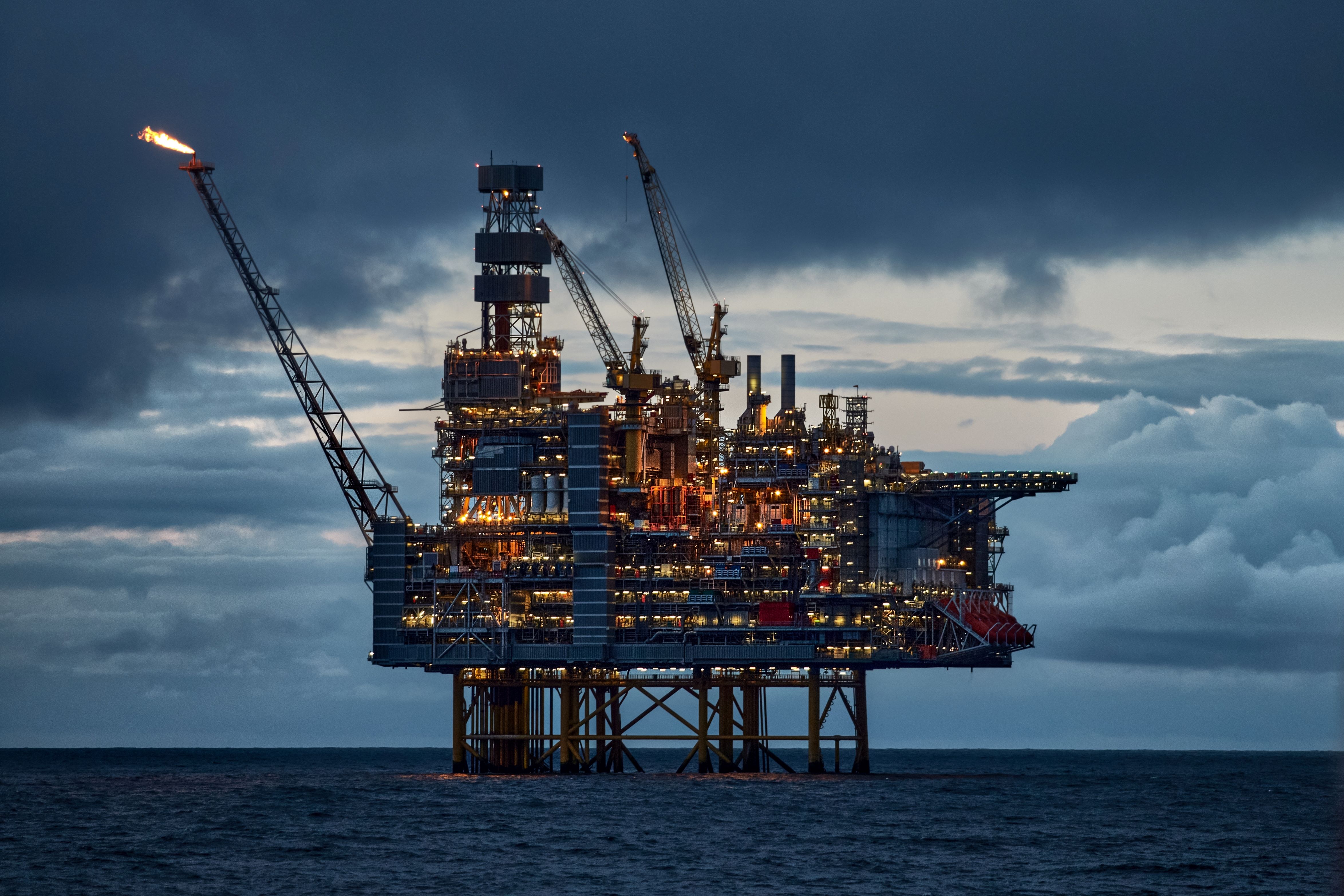 Offshore oil platform operating in open water with cranes and flare stacks