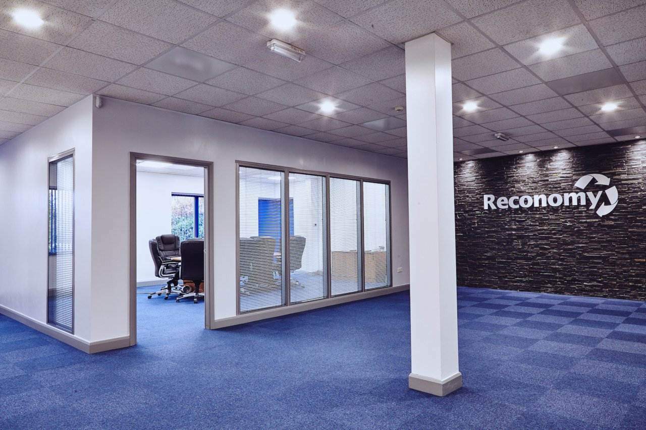 Open office floor with glazed meeting rooms and a feature logo wall.