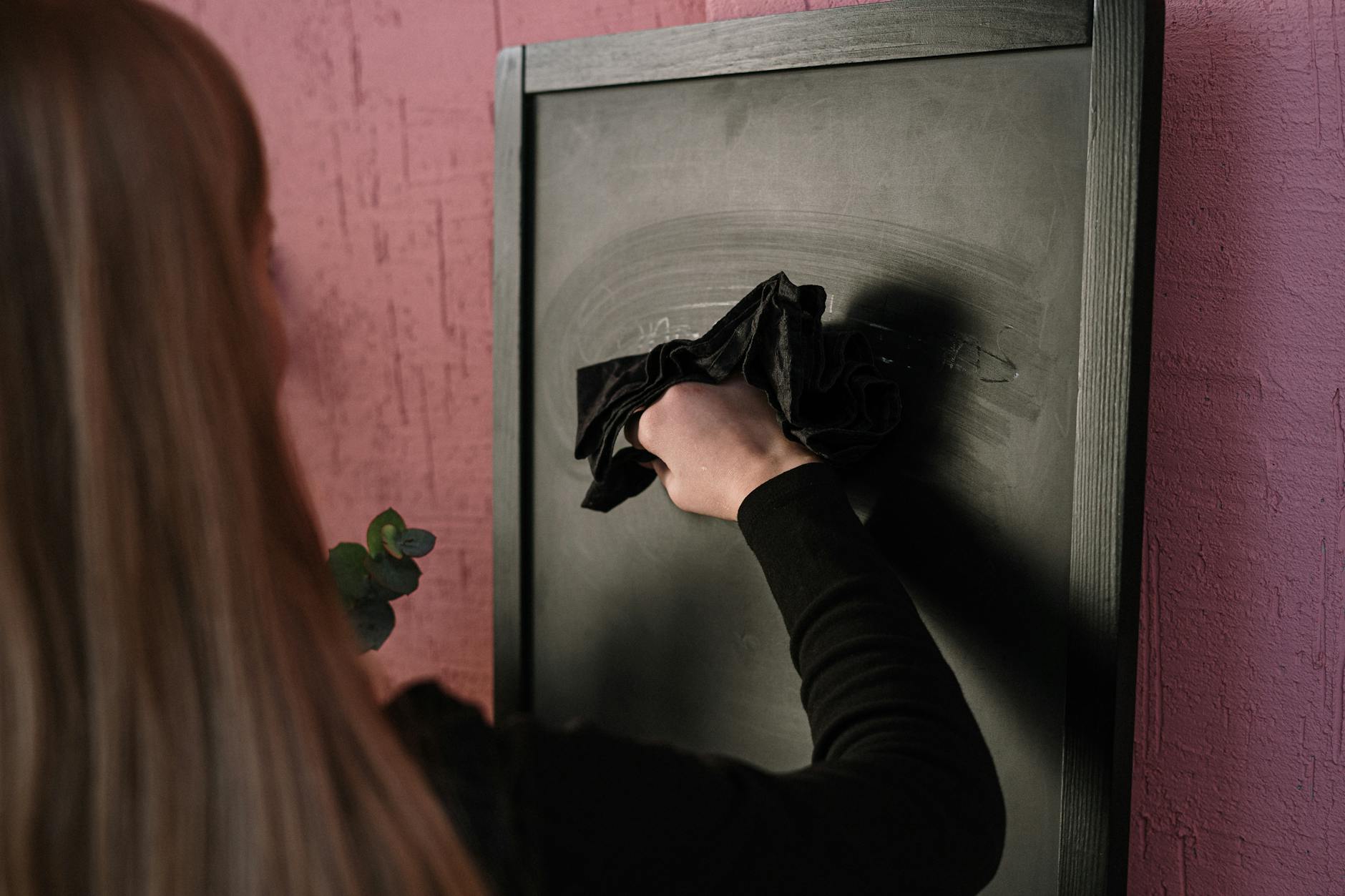 A frustrated educator looking at a laptop screen while sitting alone in a darkened classroom office.