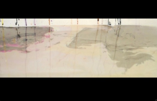 a still from a clip of a liquid reflective surface reflecting colors stripes draining on a wall