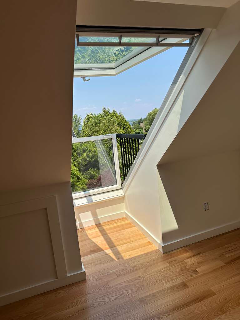 Smiling young man with curly hair, wearing a dark hoodie, against a softly lit background.