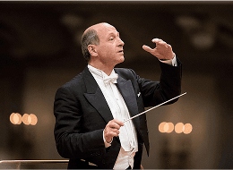 A decorative image featuring a conductor leading an orchestra in classical music performance, with the Symphony logo overlaid.