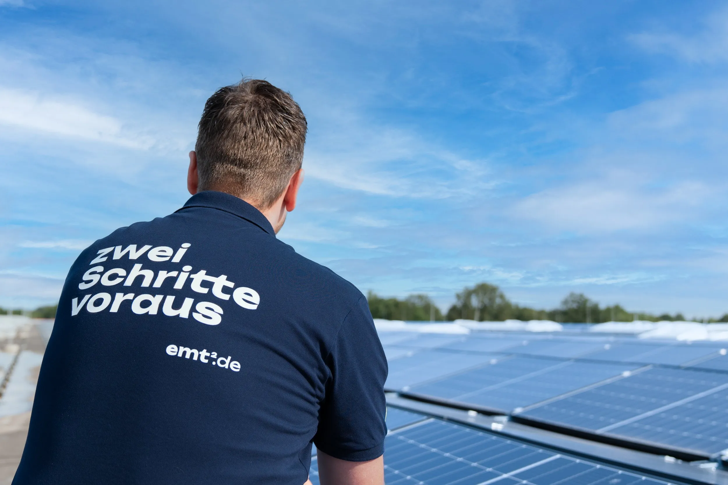 Mann mit "zwei Schritte voraus"-Shirt auf Solaranlage