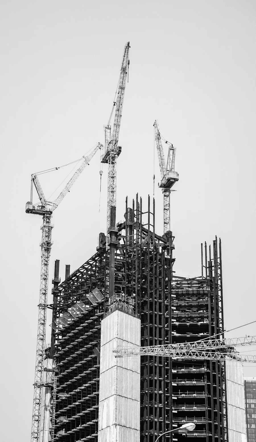 High-rise building under construction with cranes and structural framework visible.