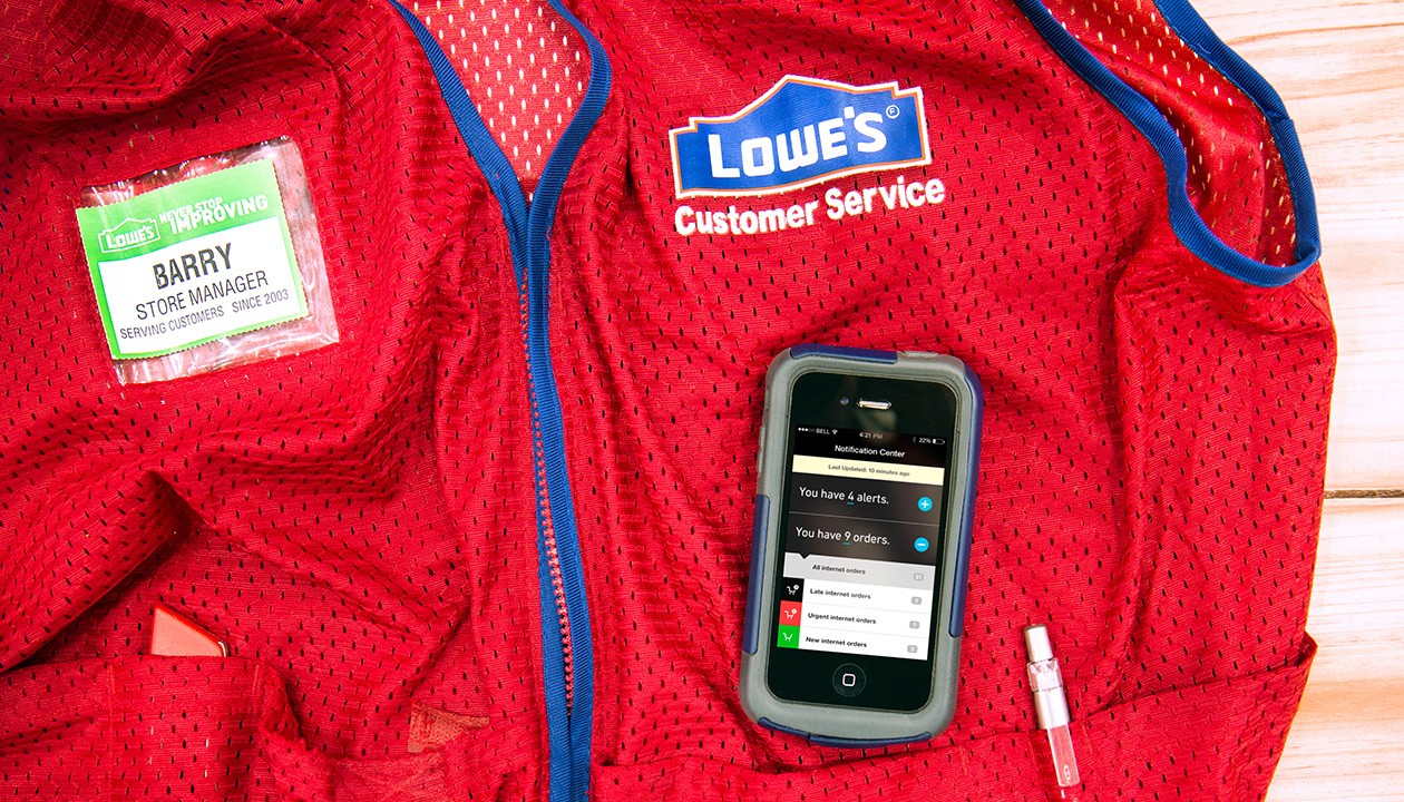 Overhead image of Lowe's employee uniform with mobile device laid on top..
